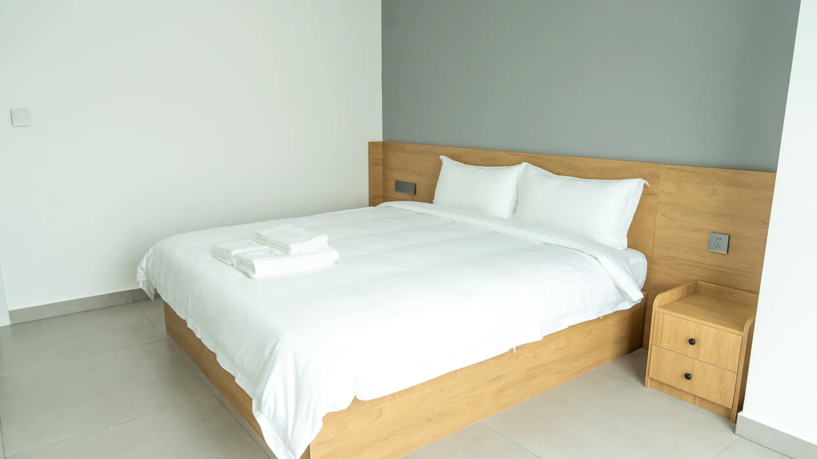 A neatly made modern hotel bed, representing a reservation viewed in a saved PDF or email