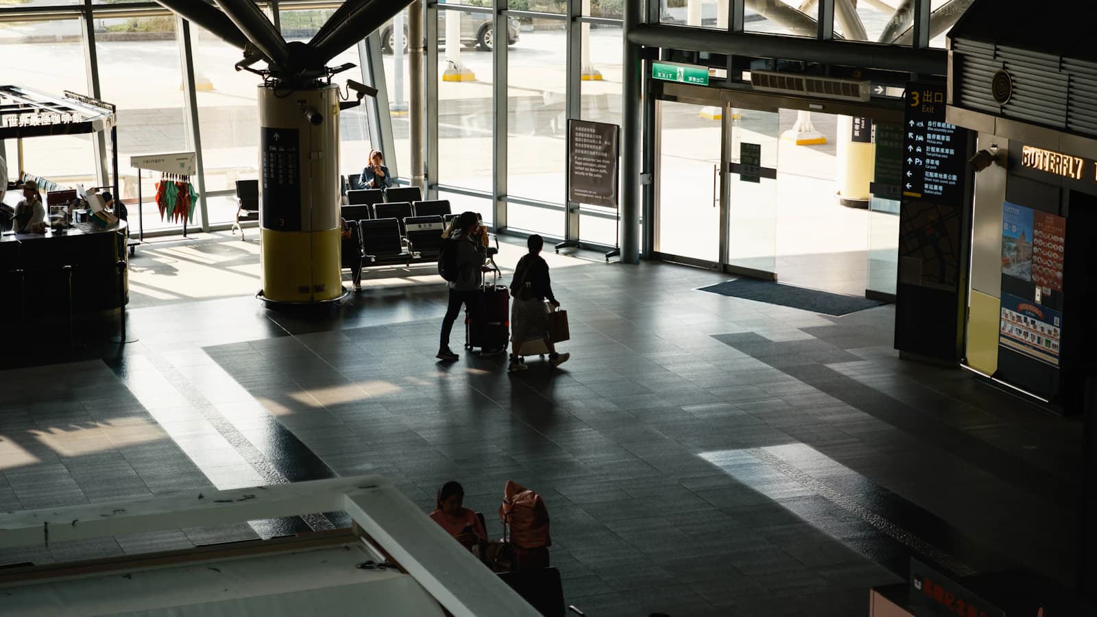 Travelers carrying luggage through a modern airport terminal between flight segments